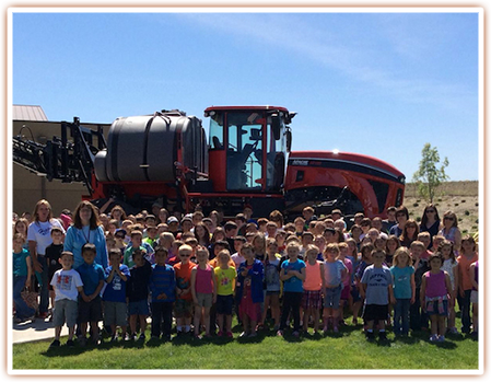Students pose for a photo in front of a sprayer display at the SAGE Center